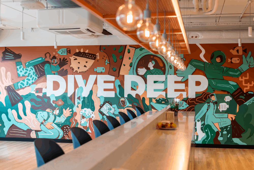Ściana biurowa z obrazami i napisem „dive deep
