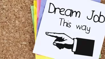 Note with 'Dream Job This Way' and a pointing hand on a cork board.