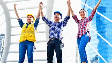 Three people holding hands, celebrating on a city bridge.