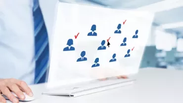 Osoba korzystająca z komputera z ikonami ludzi i znakami wyboru na ekranie.