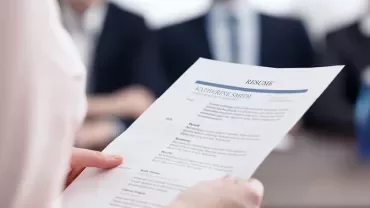 Osoba trzymająca CV podczas rozmowy kwalifikacyjnej.