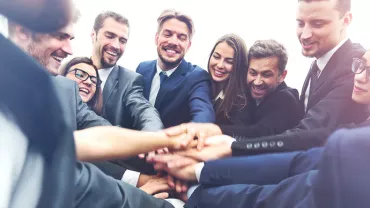 Grupa profesjonalistów łączących ręce w duchu współpracy.