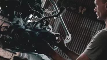 Osoba pracuje nad silnikiem motocykla w warsztacie.