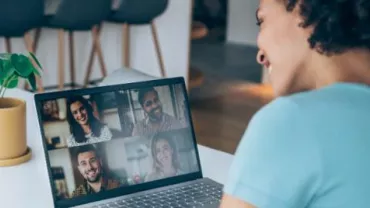 Osoba uśmiechająca się podczas rozmowy wideo na laptopie.
