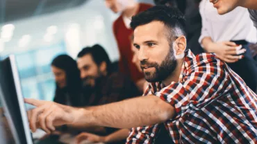 Man pointing at something on laptop screen