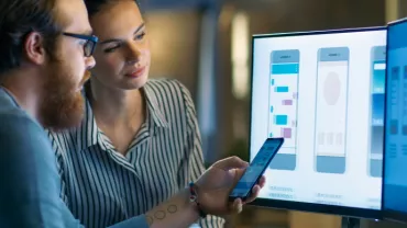 One man and one woman looking at graphics on a computer