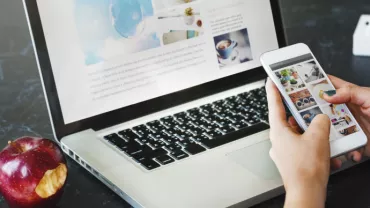 Person holding a phone in front of a laptop