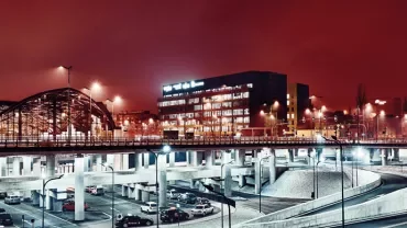 Nocny widok miasta z oświetlonym mostem i nowoczesnymi budynkami.