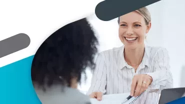 Uśmiechnięta kobieta podaje dokument innej osobie.