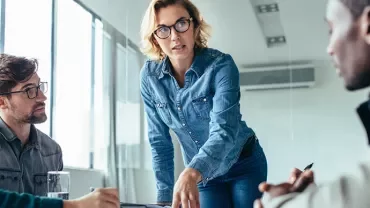 Professional woman presenting to her colleagues in a modern office setting.