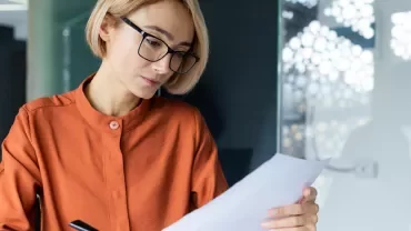Kobieta w okularach patrząca na kartkę papieru