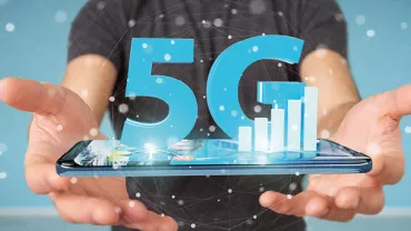 Osoba trzymająca smartfon z hologramem 5G nad nim.