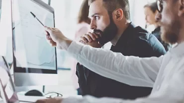 Two people analyzing data on a computer screen.