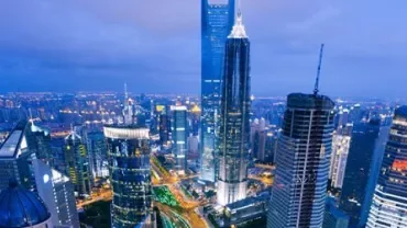 Shanghai skyline at dusk with illuminated skyscrapers.