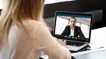 Woman in a video call on laptop with a man in a suit.
