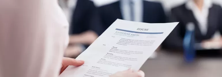 Osoba trzymająca CV podczas rozmowy kwalifikacyjnej.