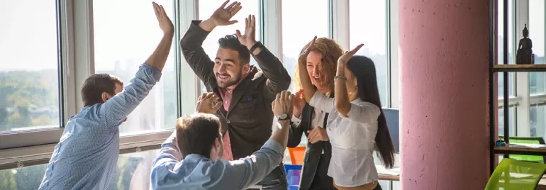 Group of people in an office celebrating with high-fives.