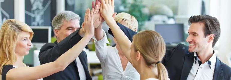 Grupa profesjonalistów robiących 'high five' w biurze.