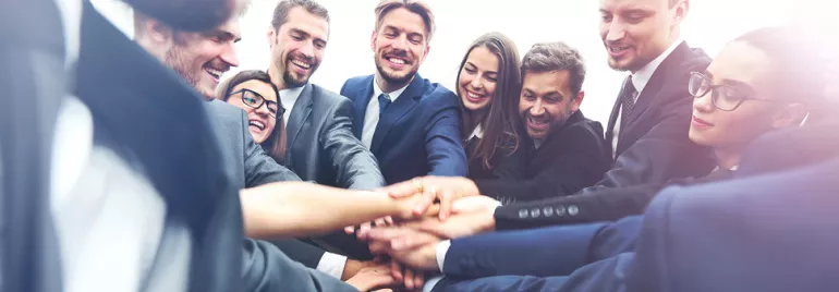Grupa profesjonalistów łączących ręce w duchu współpracy.