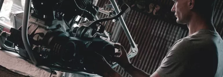Osoba pracuje nad silnikiem motocykla w warsztacie.
