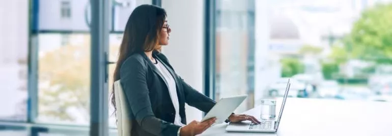 Woman with laptop and tablet in modern office.
