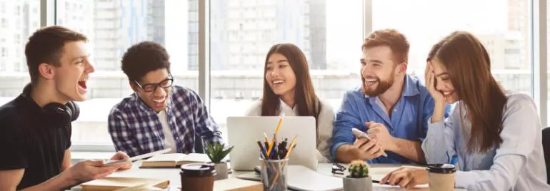 Group of friends laughing and working together at a table.