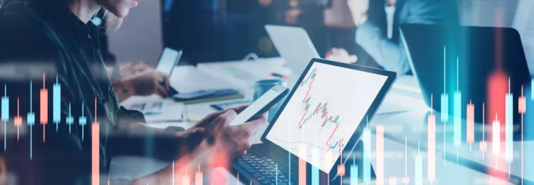 People analyzing stock charts on laptops in an office