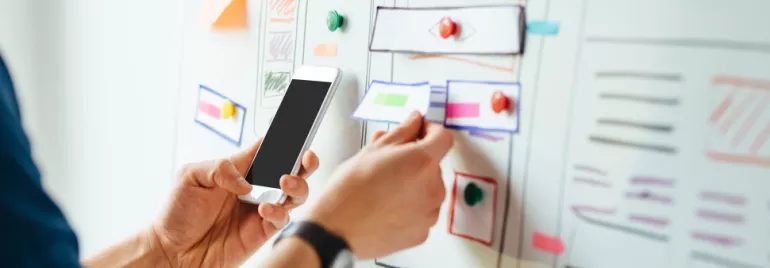 Person organizing colorful notes on a whiteboard.