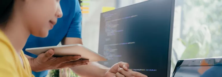 Two people discussing code on a computer screen.
