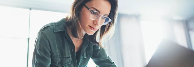 Osoba w okularach pracuje na laptopie