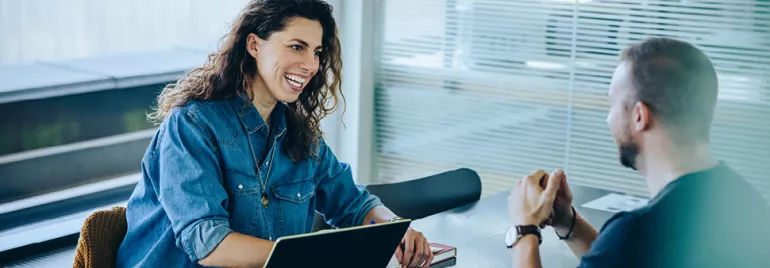 Two people having a conversation at an office table.