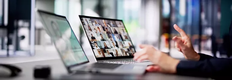 Osoba używająca laptopa do wideokonferencji w nowoczesnym biurze.