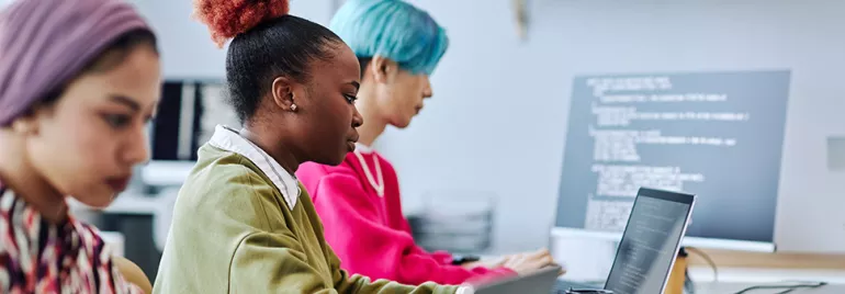 Three people working on laptops with code on screen.