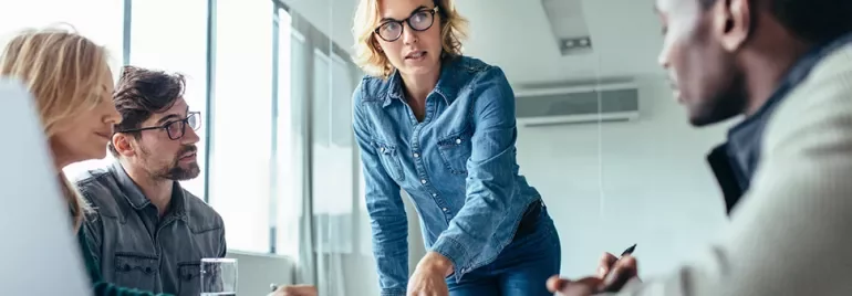 Professional woman presenting to her colleagues in a modern office setting.