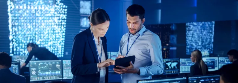 Kobieta z mężczyzną patrzą na tablet w biurze z komputerami