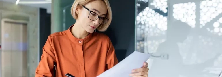 Kobieta w okularach patrząca na kartkę papieru