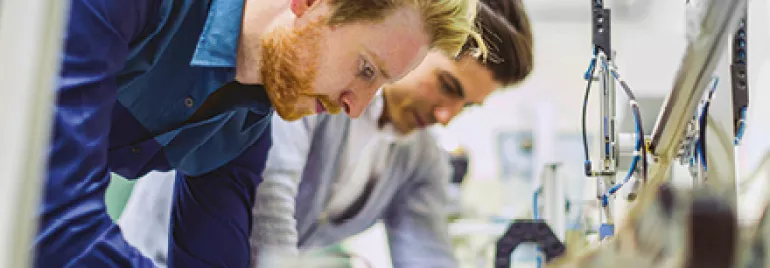 Two engineers working intensely on machinery in a workshop.