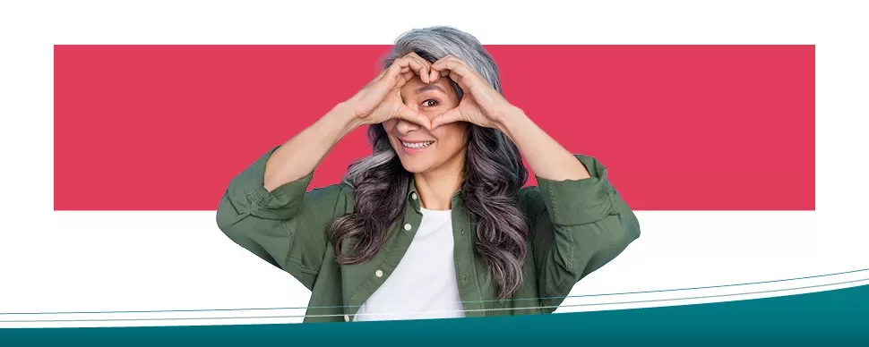 Woman smiling with heart-shaped hands in front of face.