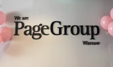 Napis PageGroup Warsaw z różowymi balonami po bokach.
