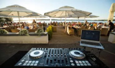 Sprzęt DJ z laptopem na imprezie plenerowej nad jeziorem.