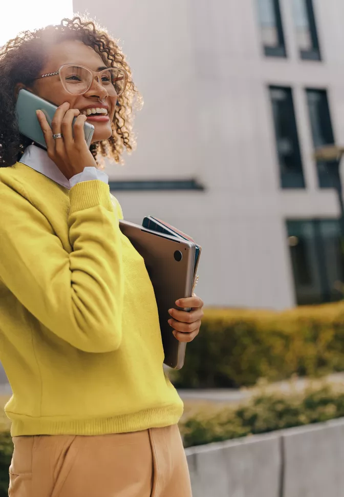 Kobieta w żółtym stroju biurowym rozmawia przez telefon.