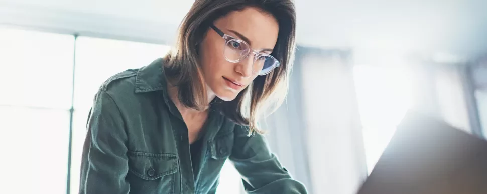 Osoba w okularach pracuje na laptopie