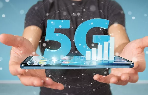 Osoba trzymająca smartfon z hologramem 5G nad nim.